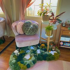 a pink chair sitting on top of a wooden floor next to a potted plant