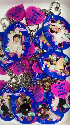 a bunch of pink and blue key chains with pictures of people on them in the shape of hearts