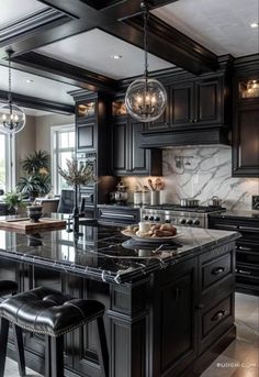 a large kitchen with black cabinets and marble counter tops, an island in the middle