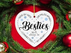 a heart shaped ornament hanging from a christmas tree with ornaments around it and the words, besties we'll connect by heart