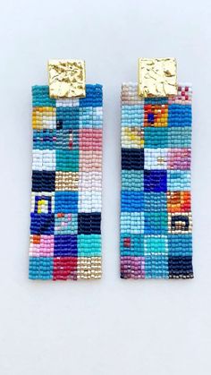 two pairs of colorful beaded earrings sitting on top of a white table next to each other