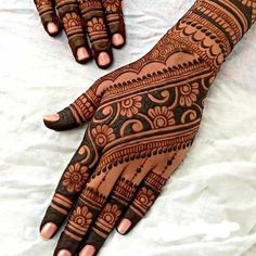 two hands with henna designs on them, one is black and the other is brown