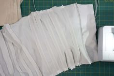 several pieces of white fabric next to a sewing machine