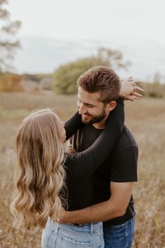 a man and woman hugging in the middle of a field