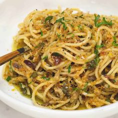 a white bowl filled with pasta and olives