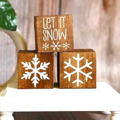 three wooden blocks with snowflakes on them and the words let it snow written on them