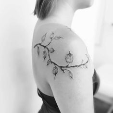 black and white photo of woman's shoulder with branch tattoo on her left arm