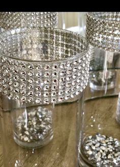 several clear glass vases sitting on top of a wooden table