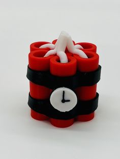 a stack of red and black legos with a clock on the front, and an octopus in the middle