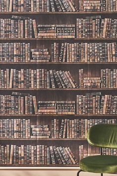 a green chair sitting in front of a bookshelf full of bookcases