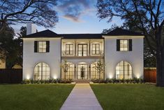 a large white house with lots of windows on the front and side of it at night