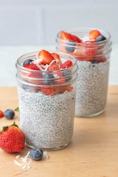 two jars filled with chia pudding and strawberries on top of a wooden table