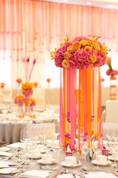 a tall vase filled with pink and yellow flowers on top of a dining room table