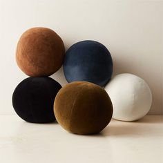 four different colored balls sitting next to each other on a white counter top with one black, one brown and one blue