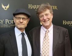 two men standing next to each other in front of a harry potter logo wallpaper