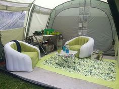 a tent with two chairs and a table in the grass next to each other on top of a blanket