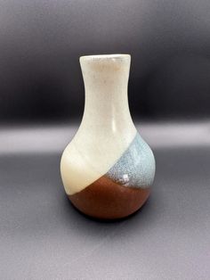 a white and brown vase sitting on top of a table