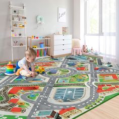 a toddler playing on the floor with his toy cars and roads in a playroom