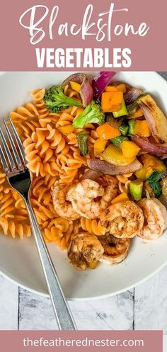 a white plate topped with pasta, shrimp and veggies next to a fork