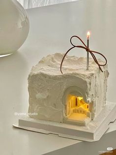 a white cake with a lit candle in it