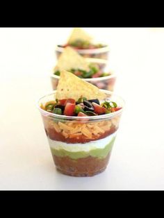 three cups filled with different types of food on top of a white tablecloth and red background