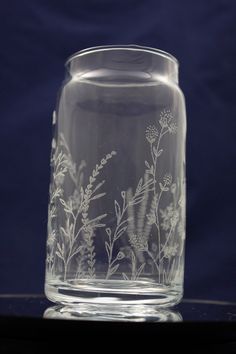 a clear glass vase sitting on top of a black table next to a blue background