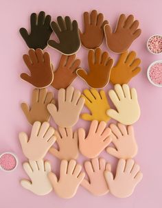 several hand shaped cookies with sprinkles in the shape of hands on pink background