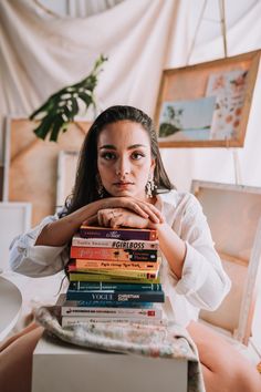 a woman sitting in front of a stack of books