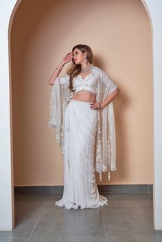 This gorgeous ivory floral machine work blouse, paired with skirt and dupatta is crafted with georgette and organza. This piece is embellished with feminine details and an undaunted elegance. Delivery Period: 2-3 weeks Elegant White Pre-draped Saree With Sheer Dupatta, Elegant White Tissue Silk Pre-draped Saree, Elegant Pre-draped Saree With Sheer Dupatta In Georgette, Elegant Pre-draped Georgette Saree With Sheer Dupatta, Georgette Lehenga With Sheer Dupatta And Cape Sleeves, Elegant White Designer Pre-draped Saree, Elegant Georgette Sharara With Unstitched Blouse, Off White Georgette Pre-draped Saree For Reception, Designer Georgette Cream Pre-draped Saree