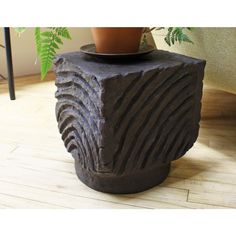 a potted plant sitting on top of a stone block in front of a couch