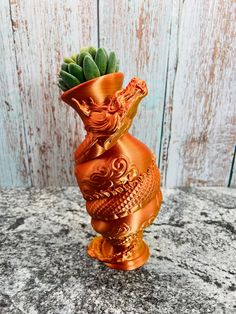 an orange vase sitting on top of a granite counter next to a wooden wall with succulents in it