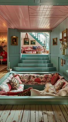 a living room filled with lots of furniture next to a stair case on top of a wooden floor