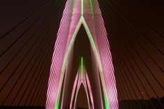 a very tall bridge lit up in pink and green