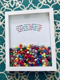 a white frame filled with lots of small colorful beads on top of a blue and white table