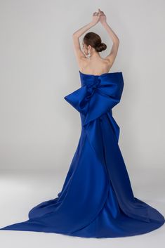 a woman in a blue dress with her hands on her head and arms behind her back