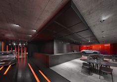 two cars are parked in an underground parking garage with neon lights on the floor and walls