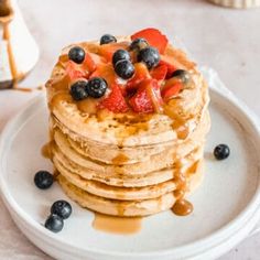 a stack of pancakes topped with fruit and syrup