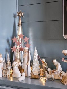 a christmas tree is on top of a mantle with figurines and other decorations