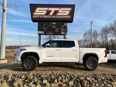 a white truck parked in front of a sign for stts jeep and truck accessories