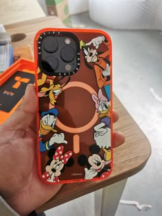 someone is holding up their phone case with mickey mouses on it and other cartoon characters