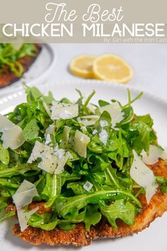 a white plate topped with lettuce and cheese next to lemon wedged bread