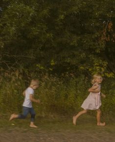 two children running in the grass near trees