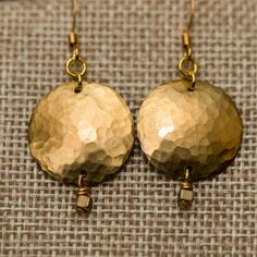 "The brass circles are hand hammered and domed to make them shiny and textured. They catch the light beautifully. There are two sizes offered in this design; the large have a brass plate that is 1.25\" diameter and the small have a brass plate that is .75\" diameter. Tiny brass squares hang below the circles, a dainty touch to balance the boldness of the larger pieces. These fun, geometric earrings can be worn with anything; they can dress up a casual outfit, or can be the statement earrings for Gold Round Soldered Earrings, Gold Round Earrings With Soldered Details, Gold Brass Round Disc Earrings, Hammered Brass Round Disc Earrings, Gold Brass Earrings With Brass Hardware, Hammered Gold Brass Earrings, Acorn Necklace, Oil Diffuser Necklace, Handmade Silver Jewellery