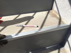 a baseball bat laying on the ground next to a metal rail with a red stick sticking out of it