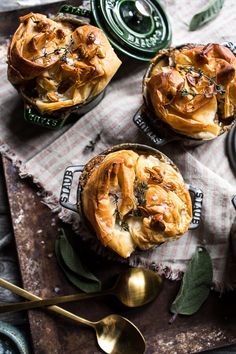 three small pies sitting on top of a table next to spoons and cups