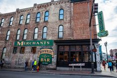 people are standing outside the merchant's restaurant in an old brick building with many windows