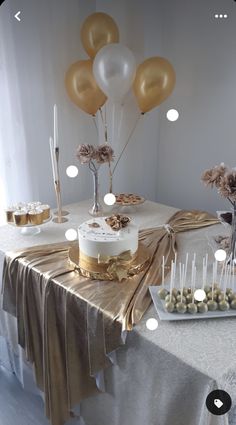 a table topped with cake and desserts covered in gold foil wrappers next to balloons