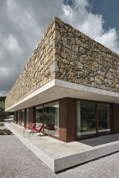 a stone building with two red chairs sitting on the ground in front of it's windows