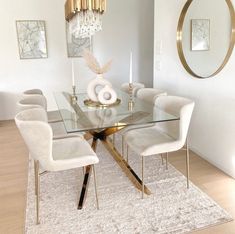 a dining room table with white chairs and a chandelier hanging from the ceiling