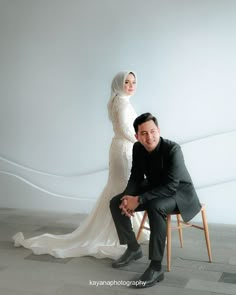 a man and woman posing in front of a white wall